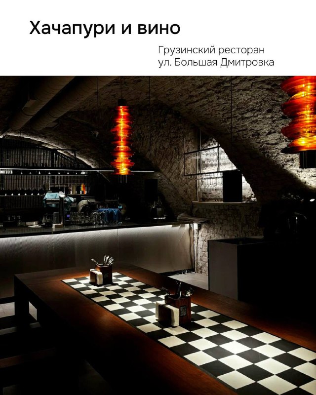 Интерьер ресторана 'Хачапури и вино': тёмный романтический зал в цокольном помещении с каменной отделкой и низким освещением.