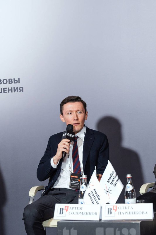 Артем Соломеннов выступает на сцене XIX Московского форума лидеров рынка недвижимости: сидит в кресле с микрофоном, видно брендирование и табличку IBC Real Estate.