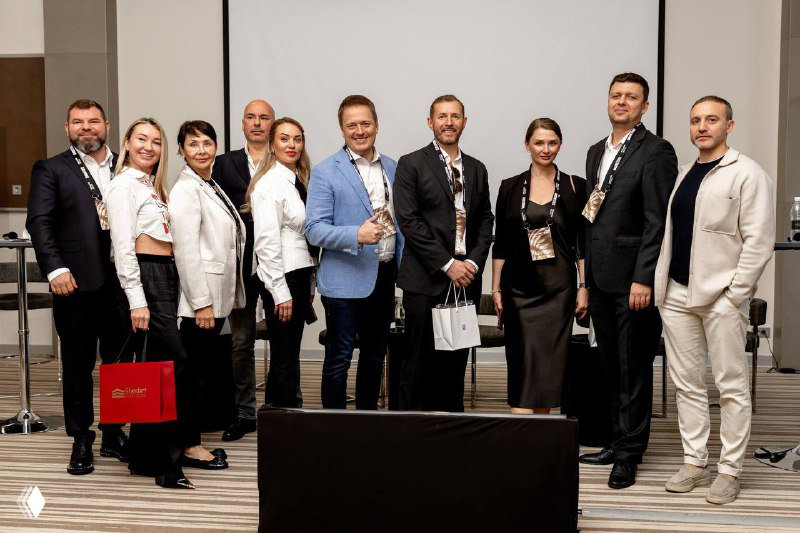 Группа участников конференции IBC Real Estate и коллеги на нетворкинге: деловые позы и непринуждённая атмосфера общения после сессий.
