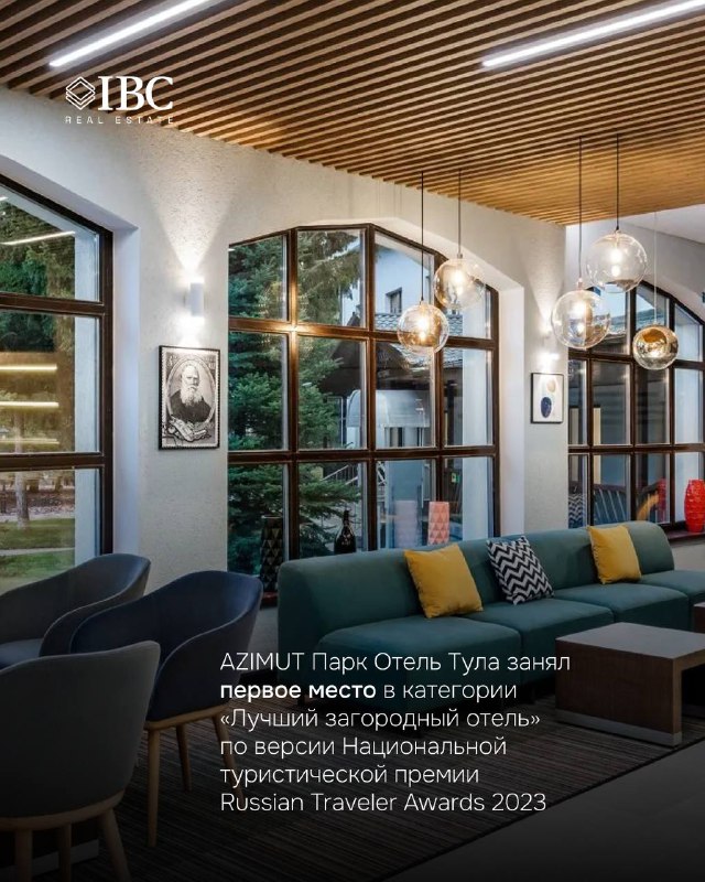 Интерьер лобби-бара AZIMUT Парк Отель Тула с панорамными окнами, деревянным потолком, дизайнерскими светильниками и мягкой мебелью.
