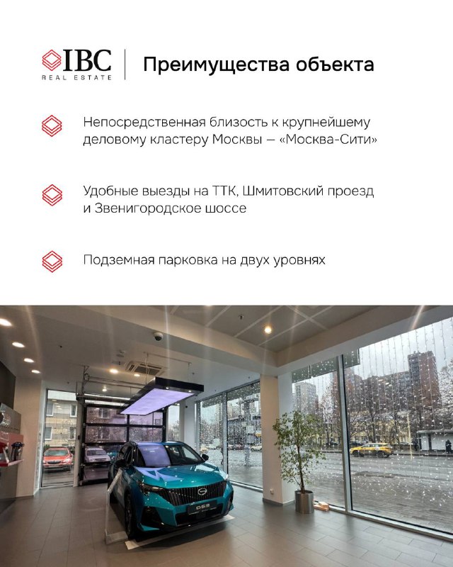 Вид изнутри шоурума на автомобили через панорамные окна: демонстрация внутренней планировки, естественного освещения и городского окружения рядом с объектом.