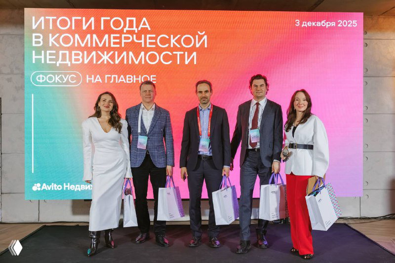 Группа спикеров и участники на фоне экрана с заголовком «Итоги года в коммерческой недвижимости», фото на память после конференции