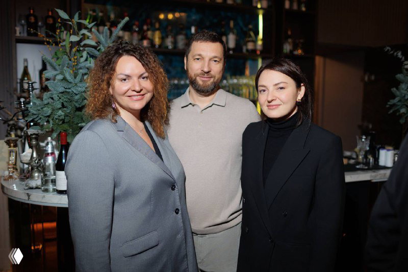 Четверо участников встречи IBC Real Estate стоят вместе и улыбаются: деловой, но дружелюбный формат общения гостей мероприятия.