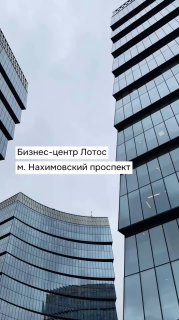 Фасады и окна современного бизнес‑центра класса А «Лотос»: стеклянные многоэтажные корпуса, вид с уровня двора на фоне неба, отражения в стекле.