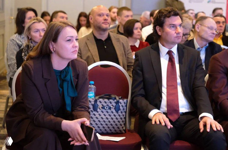 Аудитория конференции в первом ряду: слушатели внимательно следят за докладом Сергея Владимирова в деловой обстановке мероприятия.