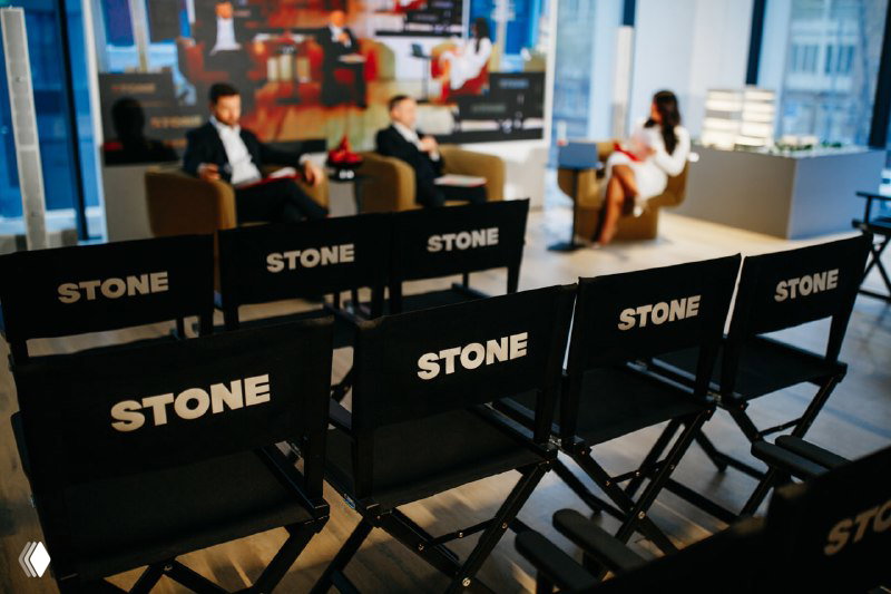 Ряд стульев с логотипом STONE в зоне презентации, вид интерьера Центрального дома продаж во время мероприятия.