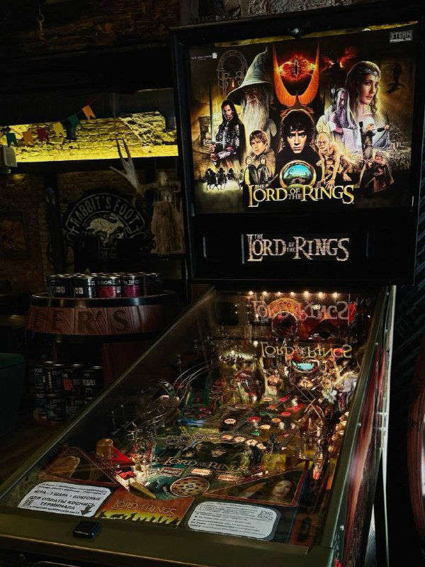 Тёмный интерьер с игровым автоматом и пинболом, заметна вывеска «Lord of the Rings» на аппарате — кадр, подходящий к гик-бару Гоблинский пунш.