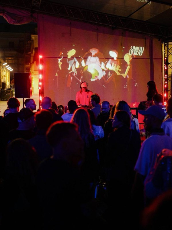 Ночной клубный снимок: диджей у пульта и толпа людей на танцполе с цветной подсветкой — атмосфера для бара «Ритмы» с электронной музыкой.