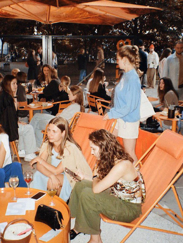 Оранжевая веранда с креслами и столиками, люди на летней террасе — визуализация открытой зоны Solids с яркой мебелью.