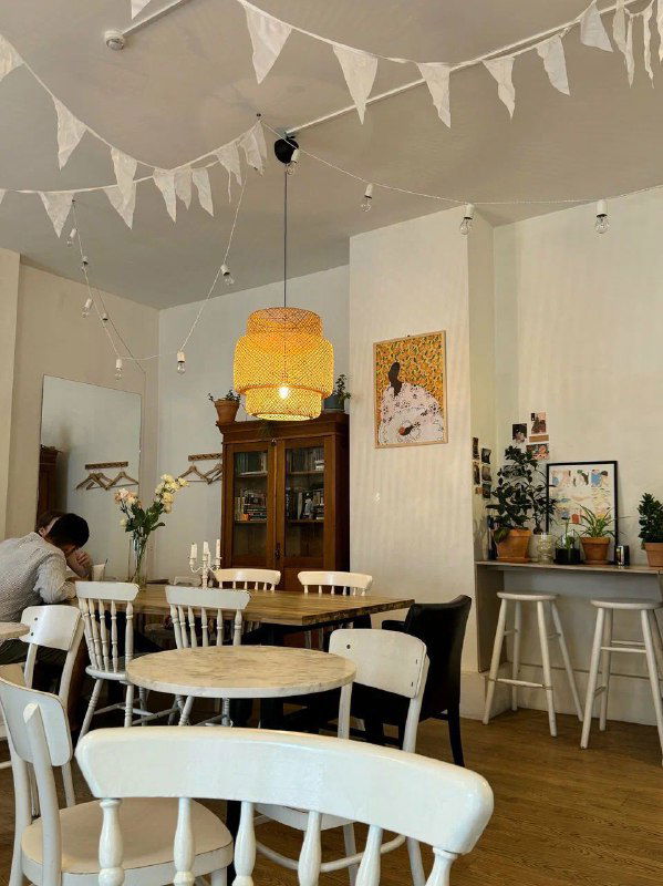 Уютный интерьер в скандинавском стиле с деревянной мебелью, подвесными лампами и флажковой гирляндой — камерная атмосфера.