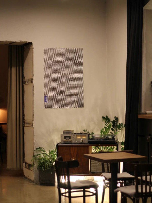 Темная уютная зона кафе с виниловым проигрывателем, плакатом на стене и растениями — атмосферный корнер для вечернего отдыха.