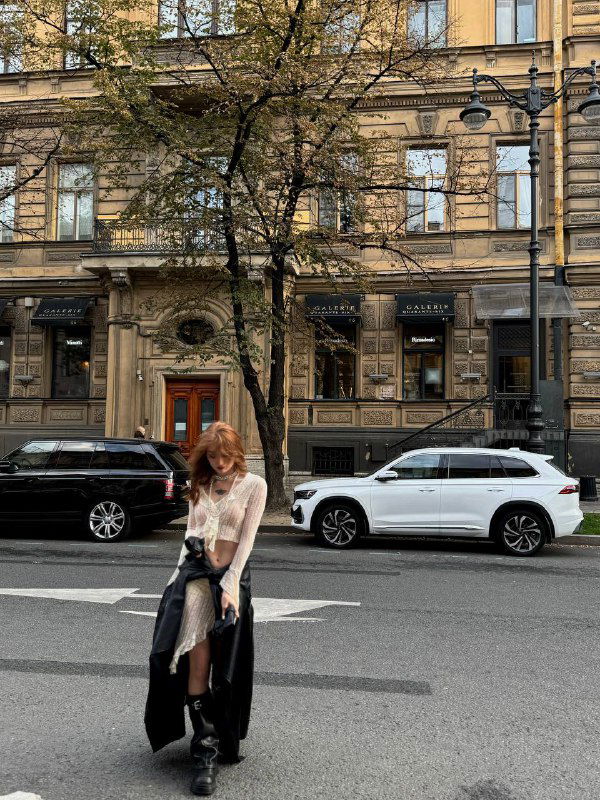 Уличная сцена: девушка позирует на фоне старинной застройки Большой Морской, на дороге припаркованы машины и видна типичная городская перспектива.