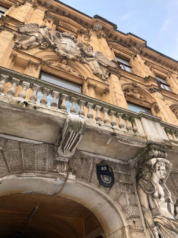 Декоративные атланты и каменная чаша на фасаде дома — скульптурные элементы, которые создают эффектные драматические кадры рядом с входом.