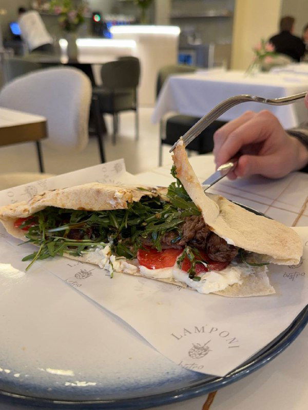 Разрезанная пьядина с начинкой из говядины, рукколы и сочного соуса на тарелке с логотипом Lamponi — видно текстуру и подачу блюда.