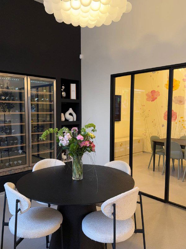 Уютный уголок ресторана Lamponi: круглый стол с вазой и цветами, стеклянная витрина и отдельная комната для праздников.