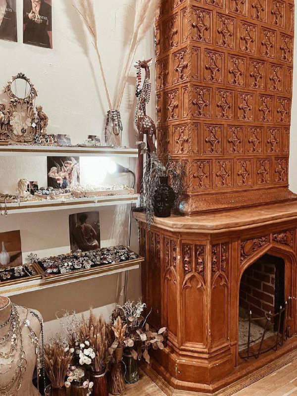 Уголок с винтажными предметами и деревянной печью или камином в интерьере — элементы антикварного оформления одного из залов особняка.