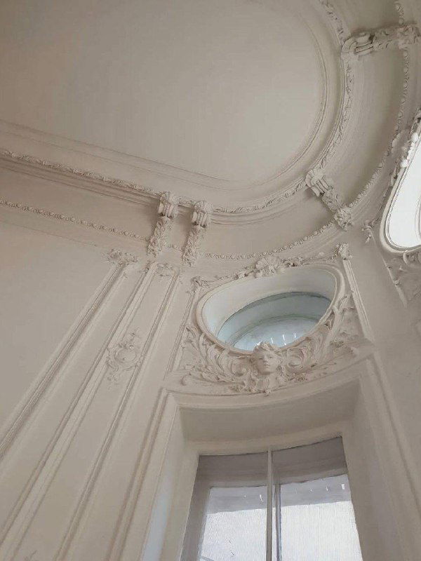 Высокий куполообразный фриз и окно в парадной лестничной клетке Особняка Слепцова с белоснежной лепниной и классическими орнаментами.