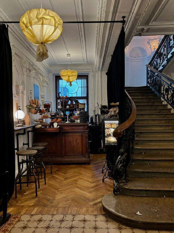 Кофейная стойка и лестница у входа в одно из заведений внутри Особняка Слепцова: сочетание коммерческого интерьера и исторической архитектуры.