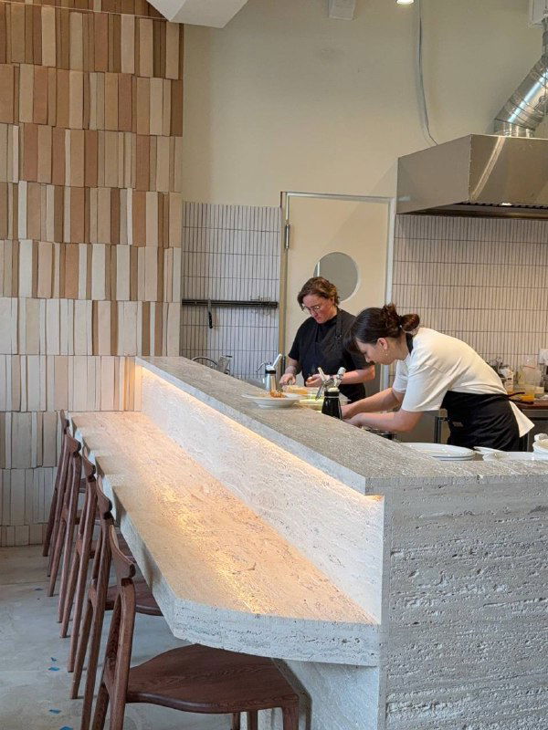 Открытая кухня и барная стойка Salty: бетонная стойка, табуреты, повара готовят на фоне терракотовой плитки и полок.