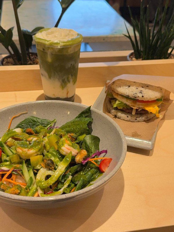 Матча-киви с сырной пенкой на фоне салата и рисового бургера — сервировка на столе внутри кафе Кореана Light.