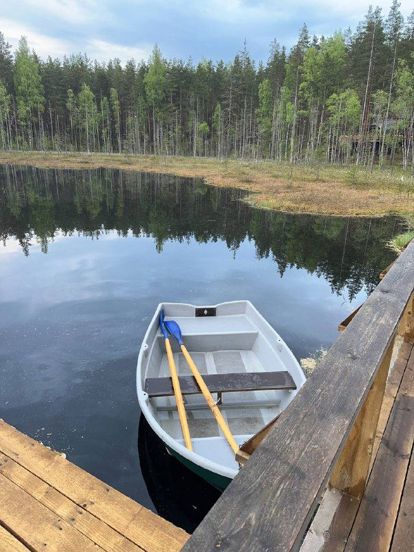 Небольшой причал и рябь на воде у озера Невидимка, рядом пришвартована деревянная лодка с вёслами — видовая баня и озёрная зона для прогулок.