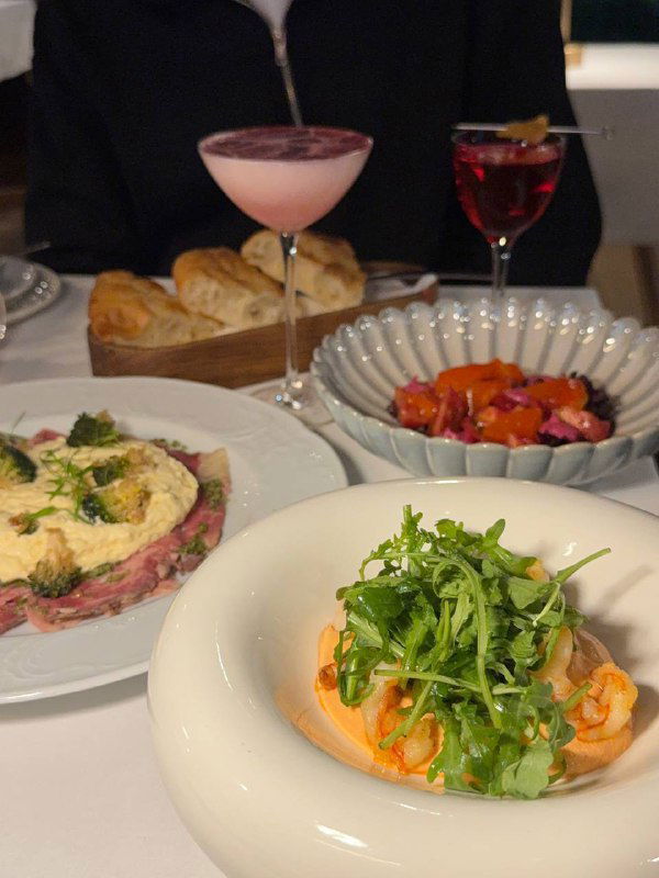 Стол с закусками и коктейлями: кремовые закуски, салаты и розовый коктейль — крупный план подачи блюд в гастро-формате ресторана.