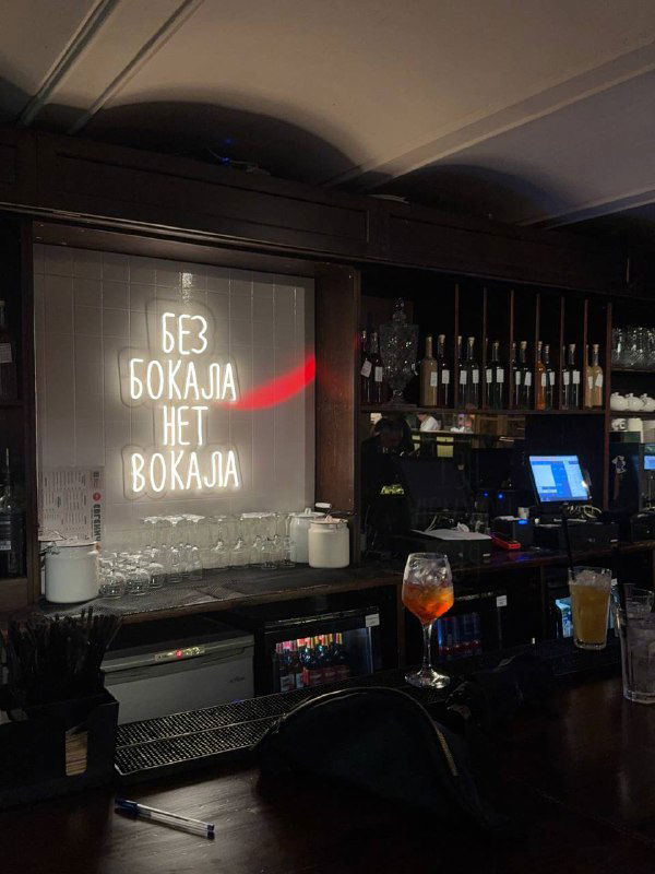 Барная стойка с подсветкой и полками для бутылок, неоновая надпись «БЕЗ БОКАЯ» создаёт атмосферу ретро-бара и вечернего освещения.