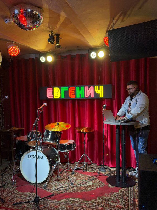 Сцена с музыкальной установкой: занавес красного цвета, логотип «ЕВГЕНИЧ» и место для живой музыки и караоке.