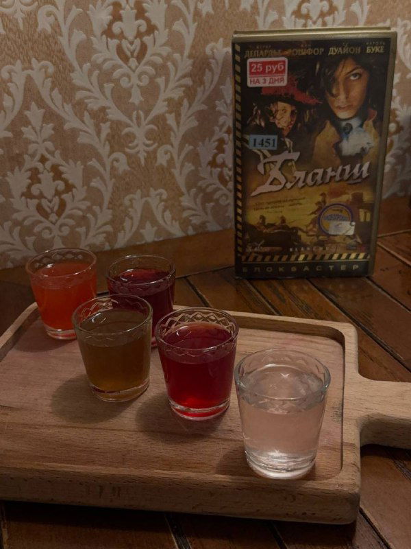 Деревянная доска с несколькими рюмками настоек разного цвета — дегустационная подача настоек в баре.