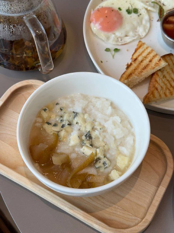 Крупный план завтрака: жареное яйцо, тосты и сервировка рядом с рисовой кашей с дорблю — детали подачи в кафе.