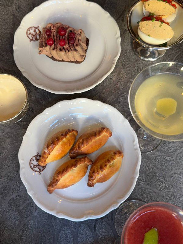 Три тарелки с закусками: тартинка с паштетом, растегайчики с бычьими хвостами и фаршированные яйца с рийетом из форели — подача на белом сервизе.