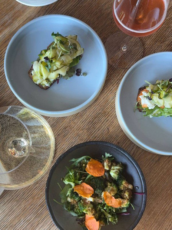 Вид сверху на несколько тарелок с закусками: брускетта и салаты, элегантная композиция подачи и бокалы вина.