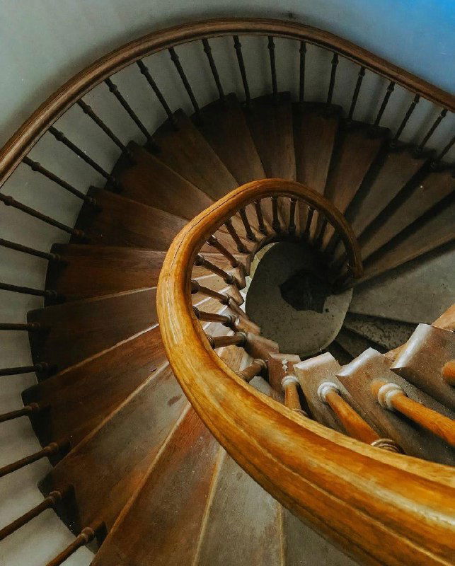Деревянная винтовая лестница внутри храма — плотный закрученный поручень и старинная фактура дерева, вид сверху на спираль.