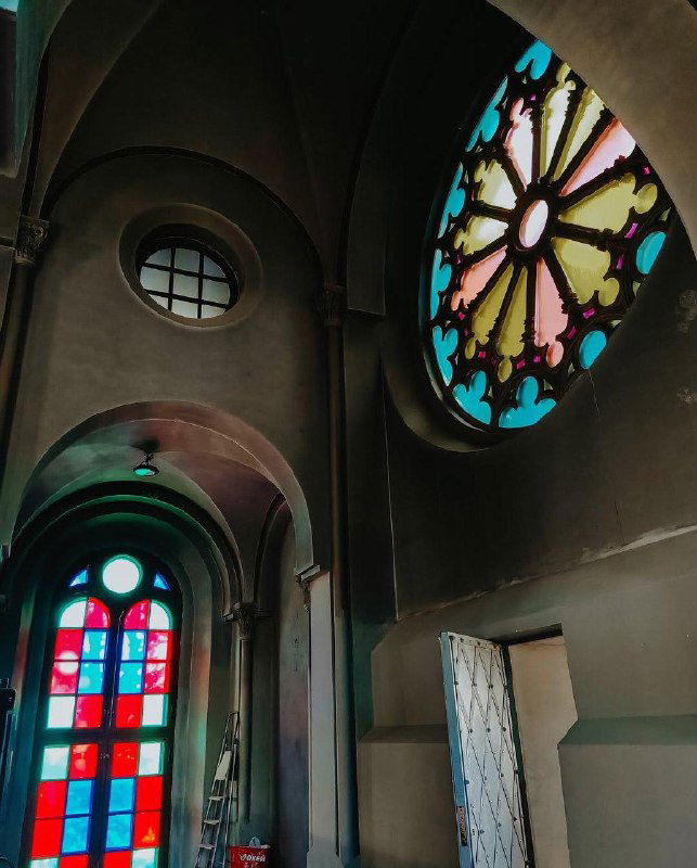 Крупный план круглого витража и арки храма: цветное стекло, мягкий свет и архитектурные детали в верхней части помещения.