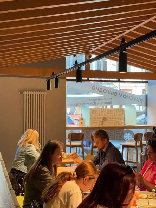 Уютная зона с деревянной потолочной конструкцией и окнами в обновлённом кафе Кореана Light, вид на внутреннюю часть и столы для двоих