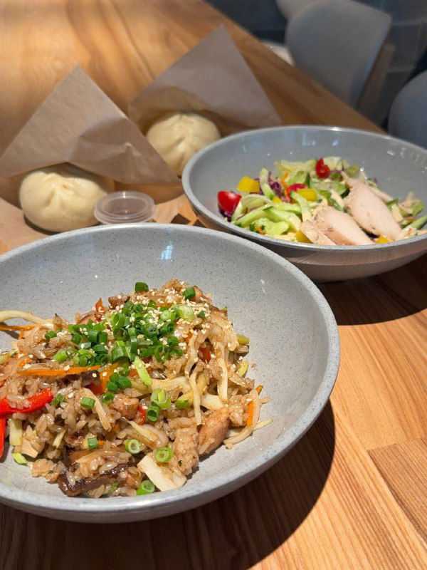 Рис с курицей терияки и ещё один боул с курицей су-вид — крупный план блюд, показаны текстуры, зелень и соусы в мисках на деревянном столе