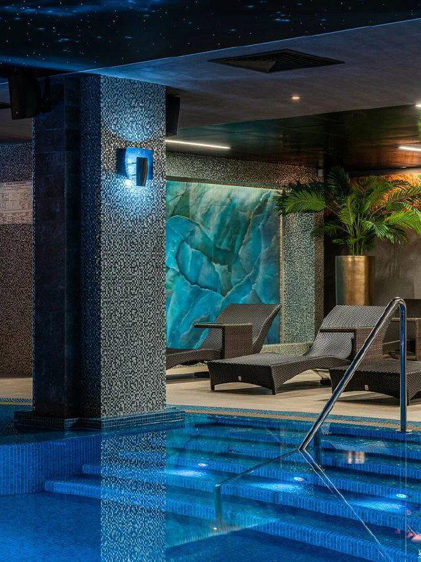 Релакс‑зона у бассейна: шезлонги, ступеньки в воду, мозаичные колонны и мягкое освещение — уютный SPA‑интерьер для отдыха.