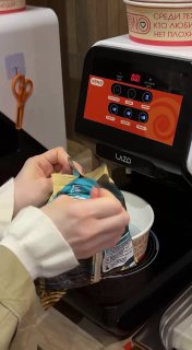 Рука держит пакет с добавкой у автоматического диспенсера для лапши — процесс самосбора и приготовления в заведении KONO.