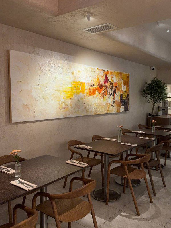 Пустой зал Teya с минималистичным декором: мягкие тона, картина на стене и аккуратные столы для спокойного завтрака.