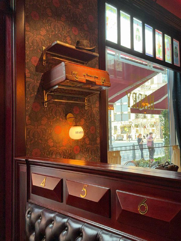 Детали интерьера: ретро-чемодан и полочка на стене, деревянные ящики с номерами, витражное окно и декоративные элементы в викторианском стиле зала паба.