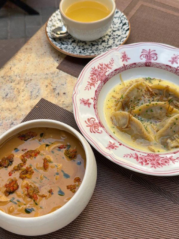 Тарелки с супом и пельменями на мраморном столе — подача блюд в традиционной посуде с тёплыми оттенками.