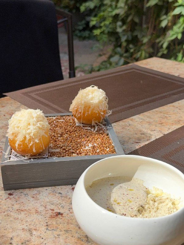 Десертная подача: маленькие пышки с трюфельной стружкой и кремовая подача в мисочке на деревянной подставке.