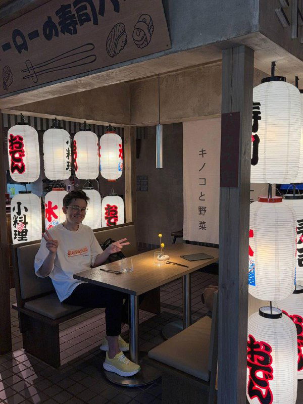 Кабинка в ресторане TAO с бумажными фонарями и гостем за столом — уютная зона для пары или небольших компаний