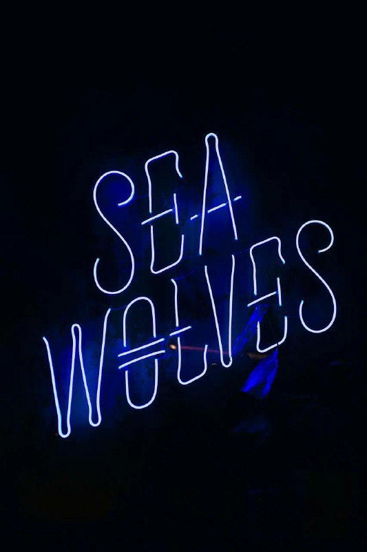 Неоновая вывеска «SEA WAVES» в тёмной зоне заведения SeaWolves — фирменный морской дизайн и логотип в интерьере клуба.