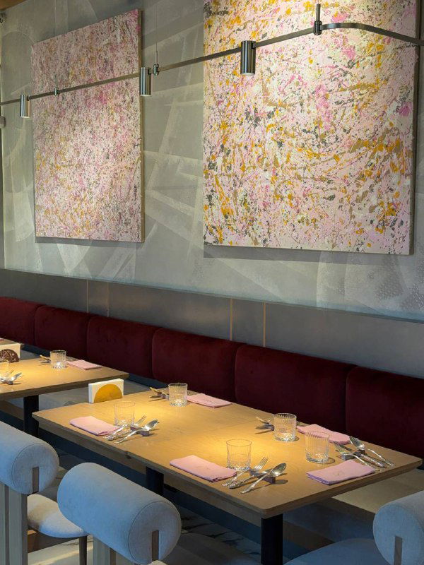 Уютный уголок зала Futurist с абстрактными картинами на стене, столиками и стульями в пастельных тонах — интерьерный фрагмент.