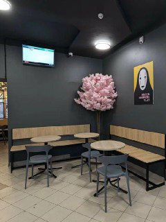 Минималистичное кафе с серыми стенами, маленькими столиками и декоративным розовым деревом — экономичный формат заведения в городе.