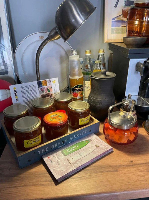 Стол с стеклянными банками, вареньем и заварочными чайниками: элементы сервировки и винтажной посуды, выставленные в кофейне-магазине.