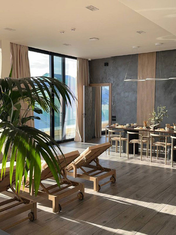 Шезлонги и столовая зона на крыше: светлое пространство с большими окнами и видом на центр Санкт‑Петербурга, место для чаепитий.