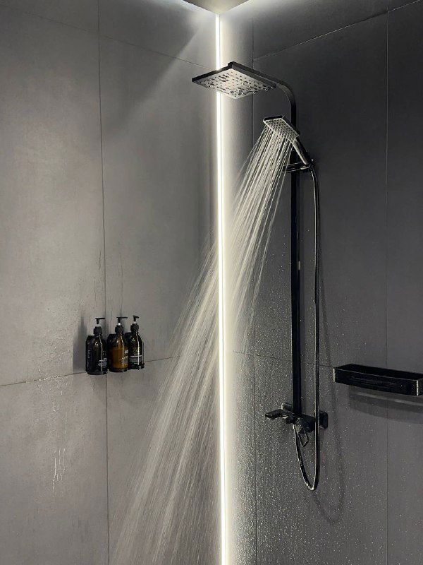 Современный душ с контрастной подсветкой и дождевой лейкой — интерьер душевой зоны спа с флаконом моющих средств на стене.