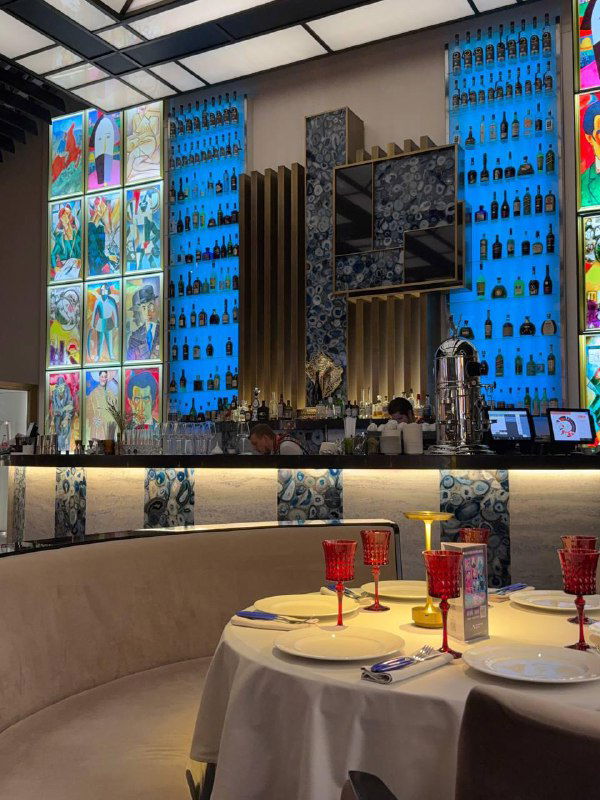 Барная зона и сервировка в ресторане «Блок»: изящные бокалы и столы на фоне витражных колонн и эффектной барной стойки